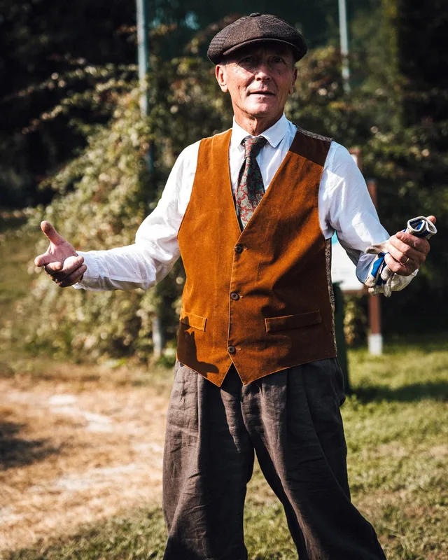 Uomo in gilet e coppola durante un evento a tema vintage sul green