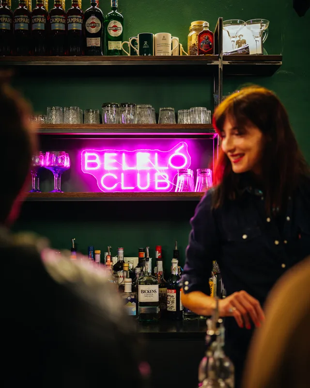 Scorcio del bancone del Bellò Club con insegna al neon e bartender al lavoro