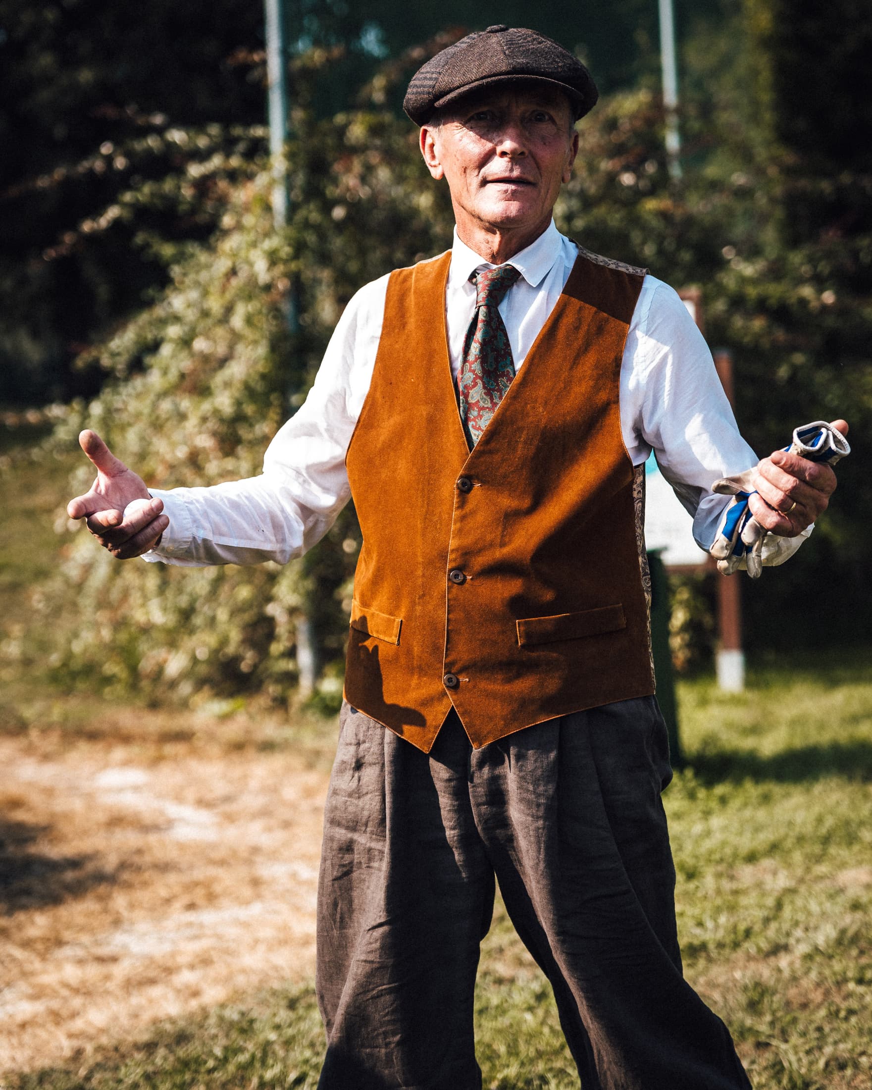 Uomo in gilet e coppola durante un evento a tema vintage sul green